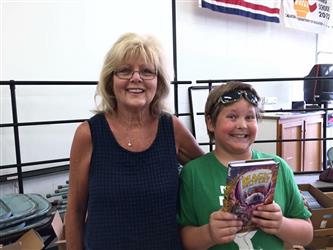 A faculty member and a student smiling while holding a book